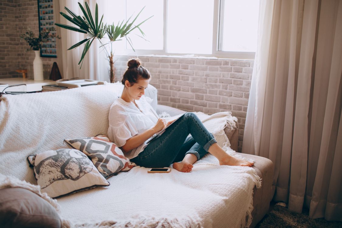 Woman using a tablet on a sofa at home